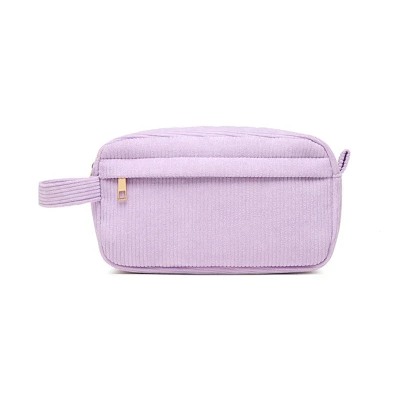 Astuccio da toilette in velluto a coste lilla con cerniera, manico laterale e design elegante. Ideale per viaggi e organizzazione cosmetici.