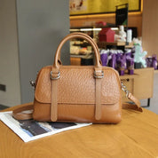 Borsa a mano in pelle marrone su tavolo di legno, design elegante con tracolla regolabile, perfetta per moda donna e accessori di lusso.