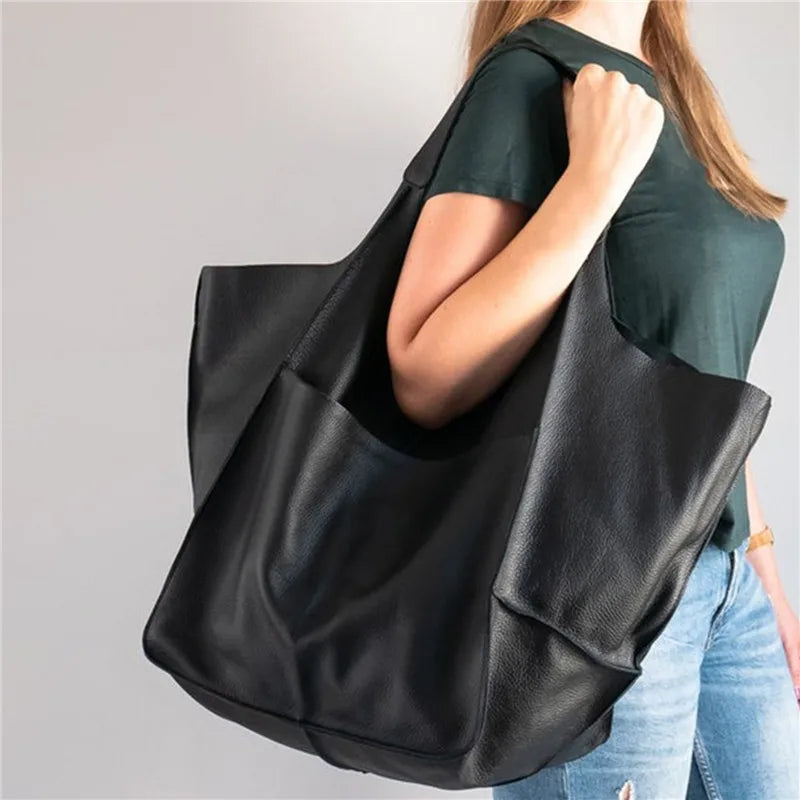 Donna con borsa shopper in pelle nera, design elegante e spazioso, ideale per moda casual e quotidiana. Accessorio di tendenza per ogni occasione.