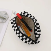 Astuccio a scacchi bianco e nero aperto, contenente penne e un flacone spray. Accessorio moda pratico per scuola o ufficio.
