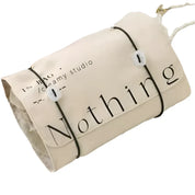 Sacca in tela beige con scritta "Nothing", chiusura a corda, design minimalista. Ideale per shopping, viaggi, moda sostenibile.