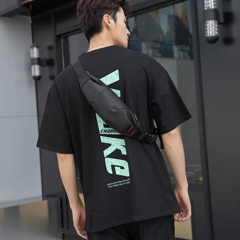 Giovane uomo con marsupio nero indossa t-shirt nera con scritta verde, all'aperto. Moda casual uomo, accessori streetwear, stile urbano.