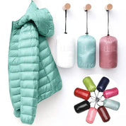 Giacca piumino ultraleggero verde acqua appesa, con sacchetti compatti in vari colori. Ideale per viaggi, moda outdoor, abbigliamento invernale.