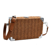 Borsa a tracolla in paglia intrecciata, design rettangolare, angoli rinforzati in metallo, chiusura superiore, stile estivo elegante e casual.