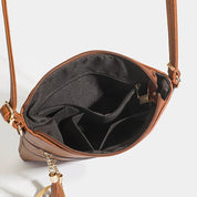 Borsa a tracolla in pelle marrone con scomparti interni neri, chiusura a zip e ciondolo decorativo. Accessorio moda donna elegante e pratico.
