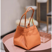 Borsa a mano in pelle arancione su tavolo rosa, design elegante e moderno, perfetta per moda femminile, accessorio di tendenza 2023.