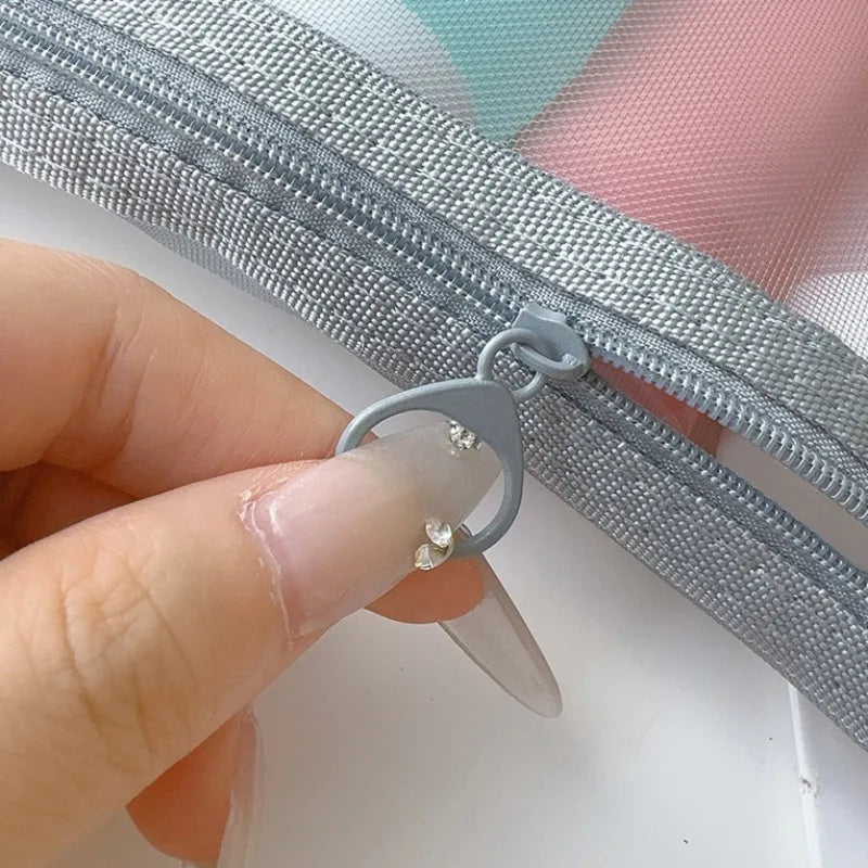 Mano che apre una cerniera grigia su una borsa trasparente. Accessorio moda, borsa organizer, chiusura lampo resistente.