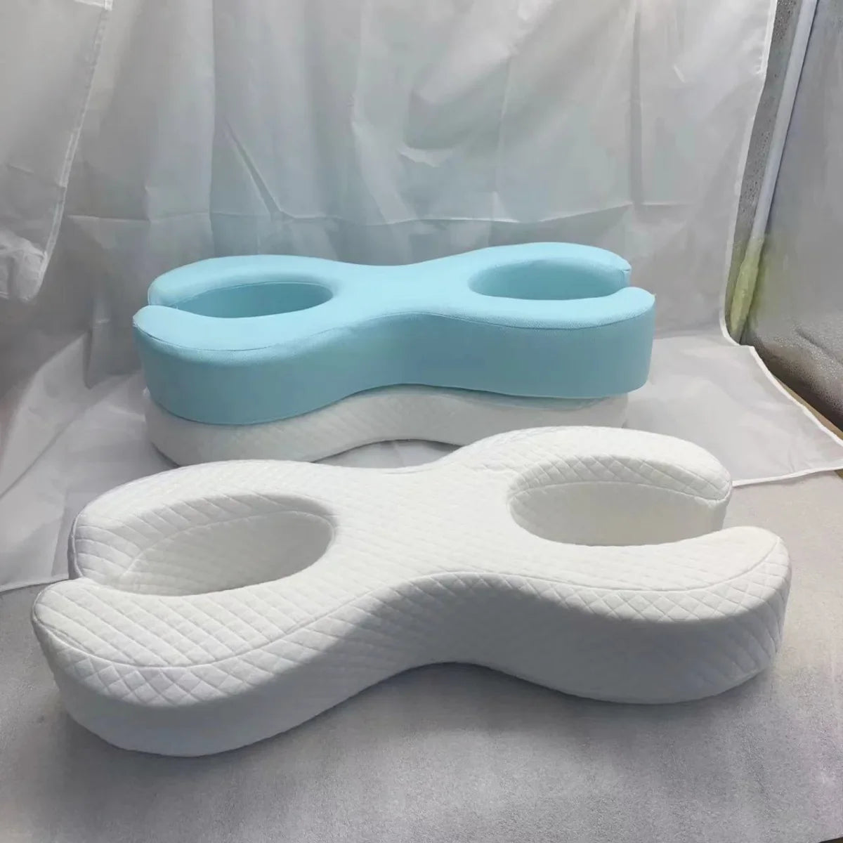 Cuscini ergonomici in memory foam a forma di farfalla, uno bianco e uno azzurro, ideali per supporto cervicale e comfort durante il sonno.