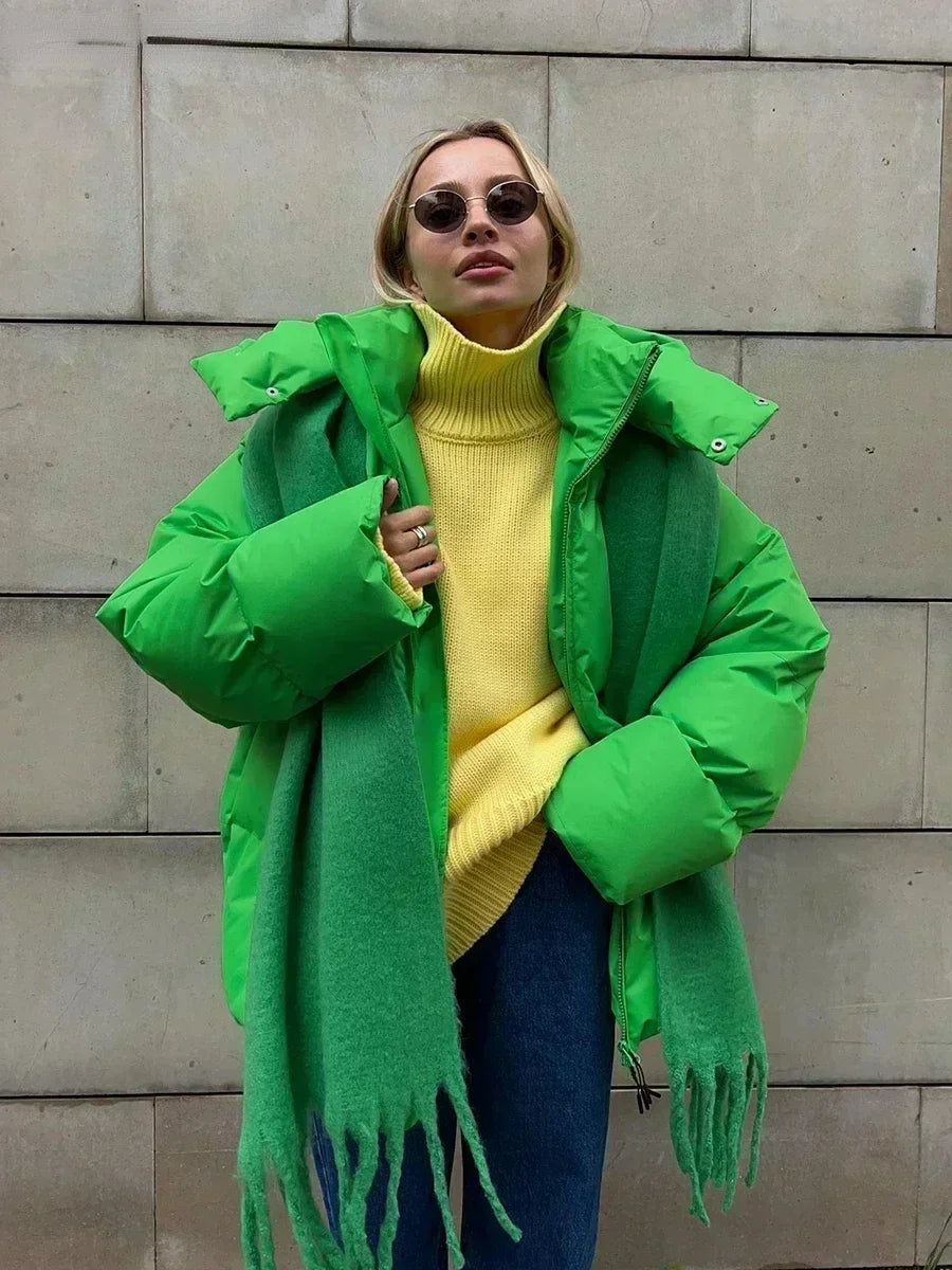 Donna con giacca verde brillante, maglione giallo, sciarpa verde e occhiali da sole. Moda invernale, abbigliamento casual, stile urbano.