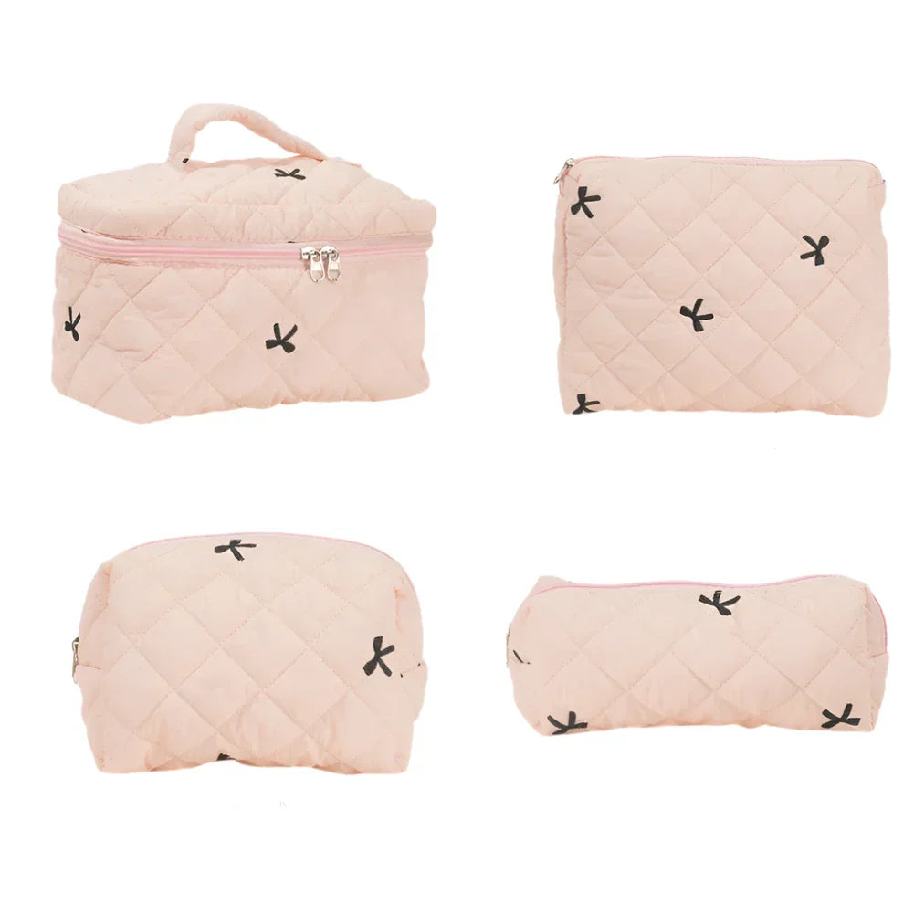 Set di quattro borse da viaggio trapuntate rosa, con cerniera e motivi a croce neri. Ideali per cosmetici e accessori. Eleganti e pratiche.