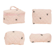 Set di quattro borse da viaggio trapuntate rosa, con cerniera e motivi a croce neri. Ideali per cosmetici e accessori. Eleganti e pratiche.