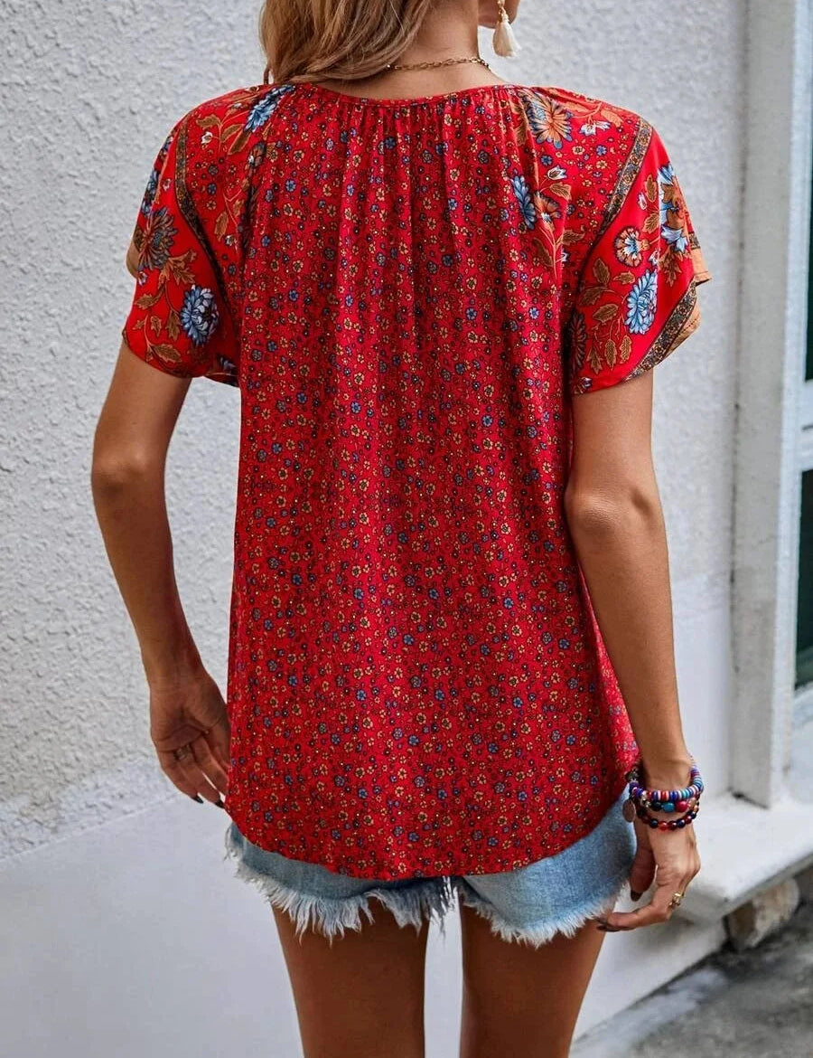 Donna con blusa rossa a fiori, maniche corte, abbinata a shorts di jeans. Moda estiva casual, abbigliamento femminile trendy.