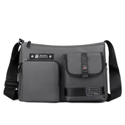 Borsa a tracolla grigia multifunzione con tasche frontali, chiusura a zip, design moderno, ideale per uomo e donna. Accessorio moda pratico e versatile.
