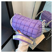 Borsa a tracolla trapuntata viola, design moderno, con manico a righe bianche e nere, su sfondo di specchio e mobili scuri.