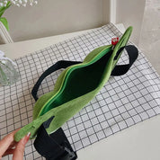 Marsupio verde in tessuto su tovaglia a quadri, con cerniera aperta e cinturino nero regolabile. Accessorio moda casual e pratico.