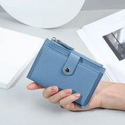 Portafoglio donna in pelle blu chiaro con chiusura a bottone, design compatto, ideale per carte e contanti. Accessorio moda elegante e funzionale.