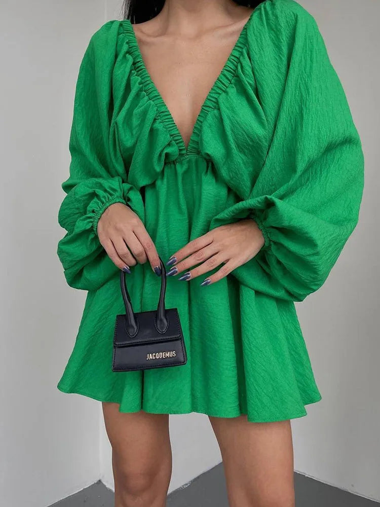 Donna con abito verde scollato e borsa nera Jacquemus. Moda elegante, abbigliamento femminile, tendenze 2023, stile contemporaneo.