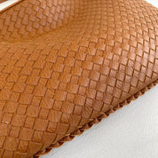 Borsa intrecciata in pelle marrone, design elegante e artigianale, accessorio moda di lusso, texture dettagliata, stile sofisticato.
