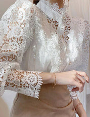 Blusa bianca in pizzo floreale, maniche lunghe, colletto alto, elegante e raffinata, perfetta per occasioni formali e moda femminile.