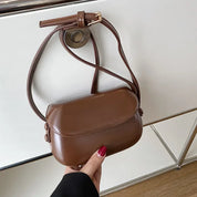 Borsa a tracolla in pelle marrone, design elegante e compatto, chiusura con patta, ideale per moda donna. Accessorio versatile e di tendenza.