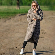 Donna con cardigan lungo a maglia beige, cappuccio, all'aperto. Moda autunnale, abbigliamento casual, stile confortevole.
