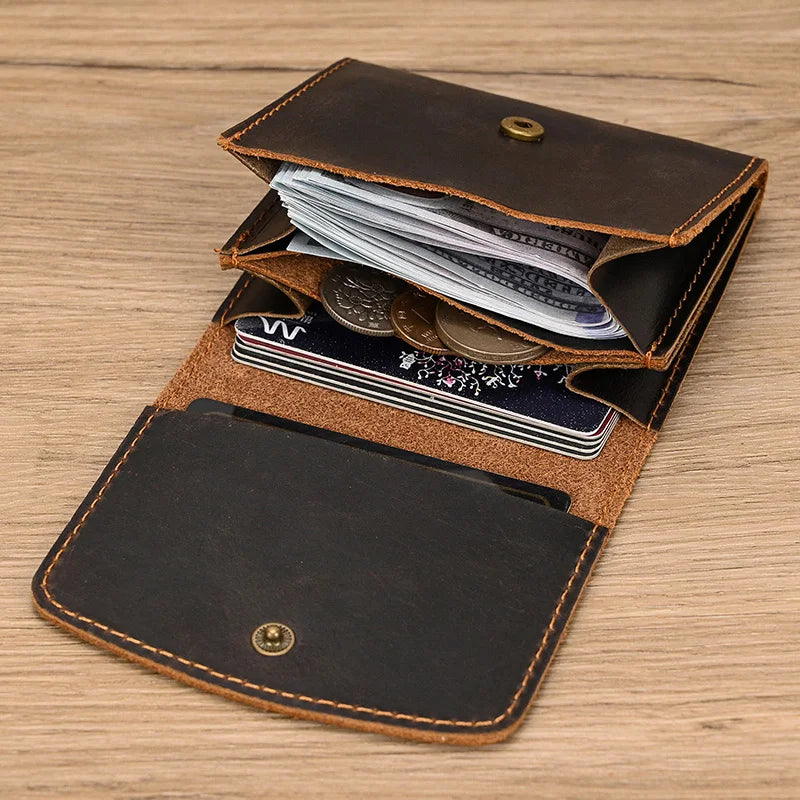 Portafoglio in pelle marrone aperto su tavolo di legno, con scomparti per banconote, monete e carte di credito. Design elegante e funzionale.