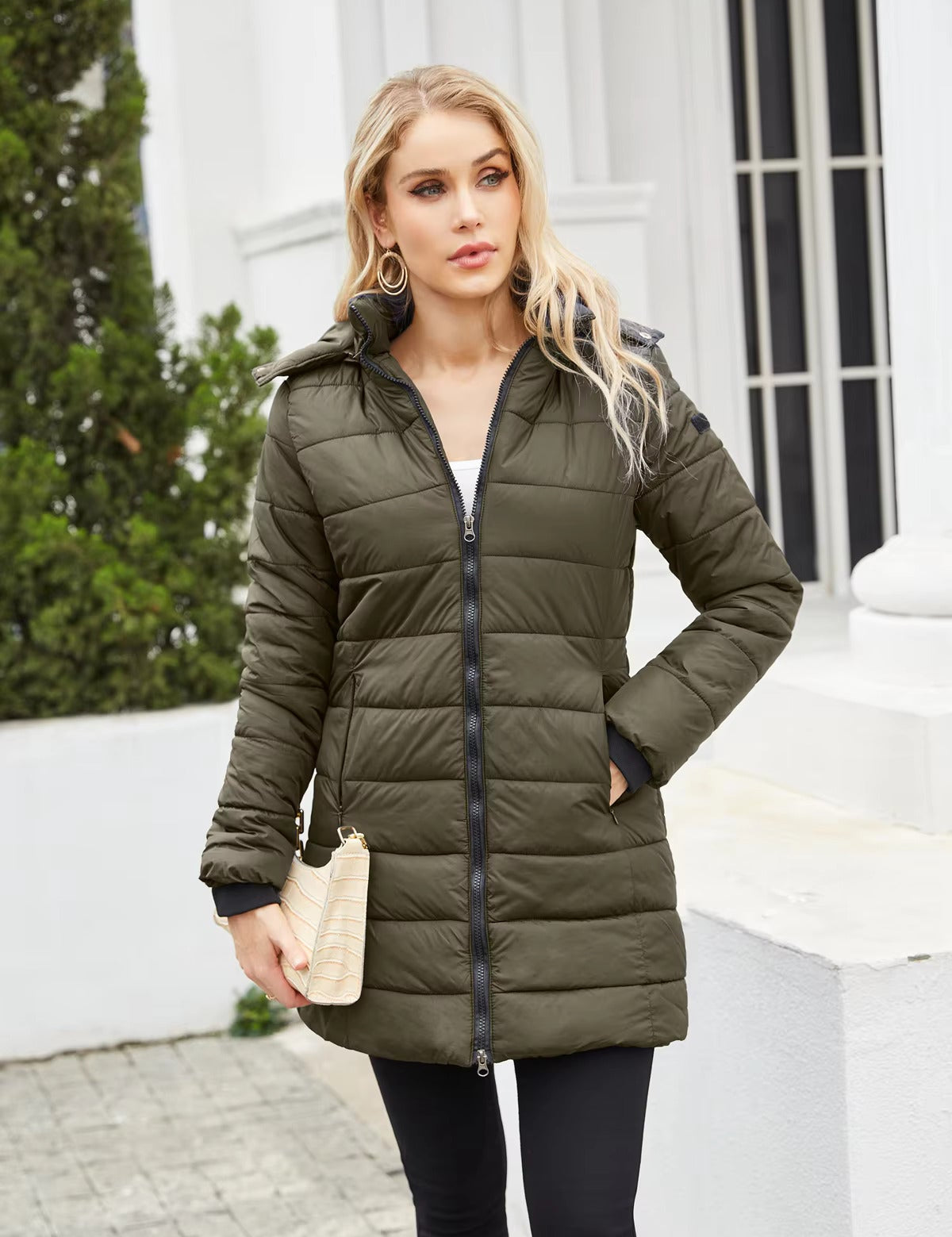Donna con cappotto invernale verde oliva, zip frontale, tasche laterali, posa all'aperto. Moda femminile, abbigliamento caldo, stile casual.