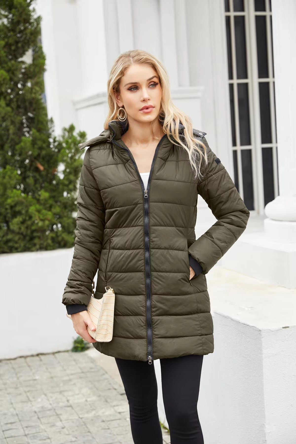 Donna con cappotto invernale verde oliva, zip frontale, tasche laterali, posa all'aperto. Moda femminile, abbigliamento caldo, stile casual.