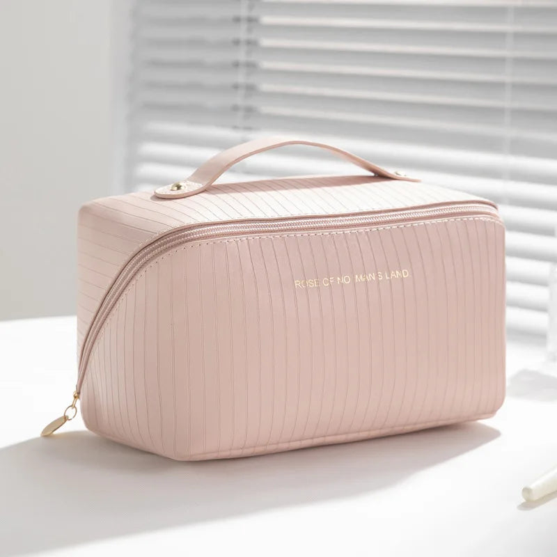 Borsa cosmetica rosa in pelle con cerniera dorata, design a righe, manico superiore. Elegante e pratica per organizzare trucchi e accessori.