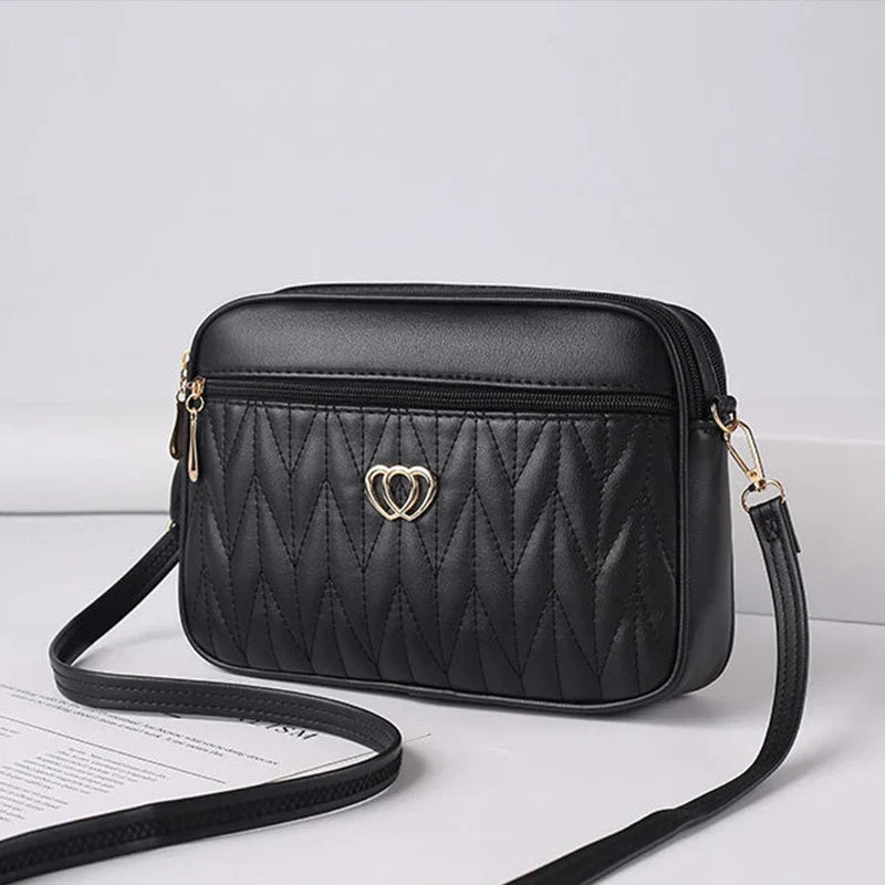 Borsa a tracolla nera in pelle trapuntata con motivo a zigzag, decorazione a cuore dorato, chiusura con zip, elegante e moderna per donna.