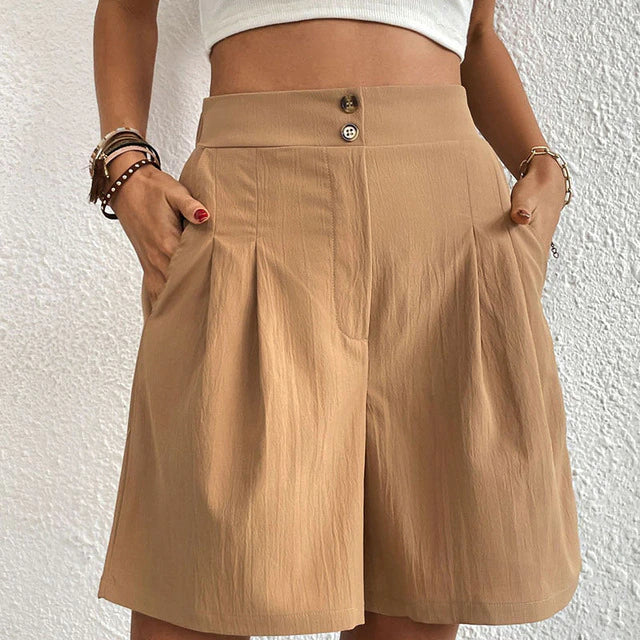 Shorts beige a vita alta con tasche, chiusura a bottone, indossati da una donna. Moda estiva casual, tessuto leggero, stile elegante.
