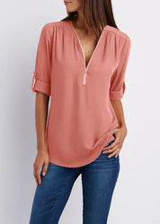 Blusa donna rosa con zip, maniche a 3/4 arrotolate, scollo a V, abbinata a jeans. Elegante e casual, perfetta per moda femminile quotidiana.