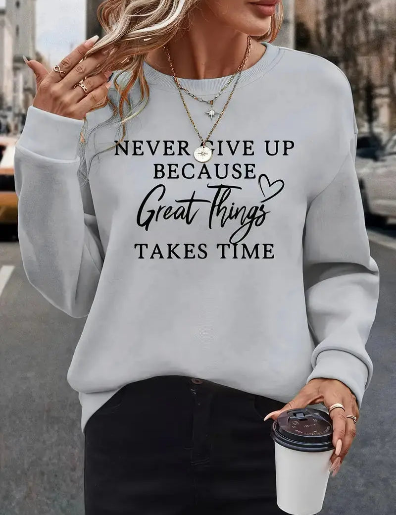 Donna con felpa grigia con scritta motivazionale, collane dorate e caffè in mano. Moda casual autunnale, abbigliamento street style.