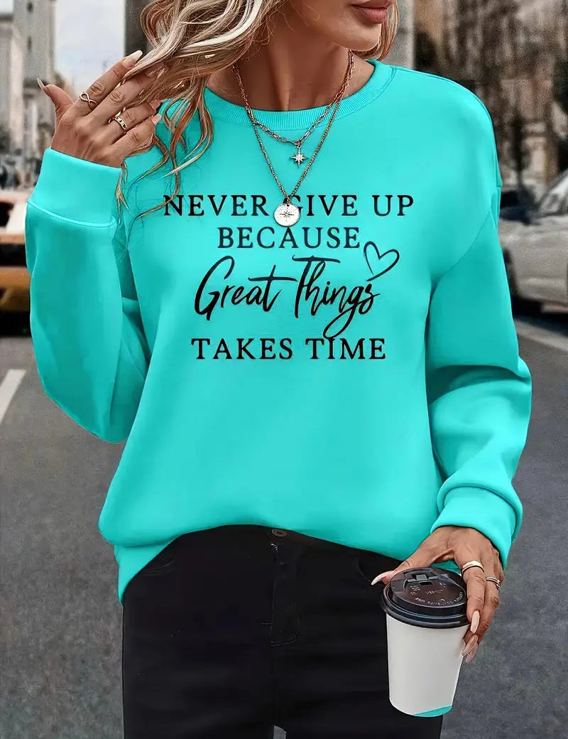 Donna con felpa turchese con scritta motivazionale, collane dorate e caffè da asporto. Moda casual, abbigliamento autunnale, ispirazione quotidiana.