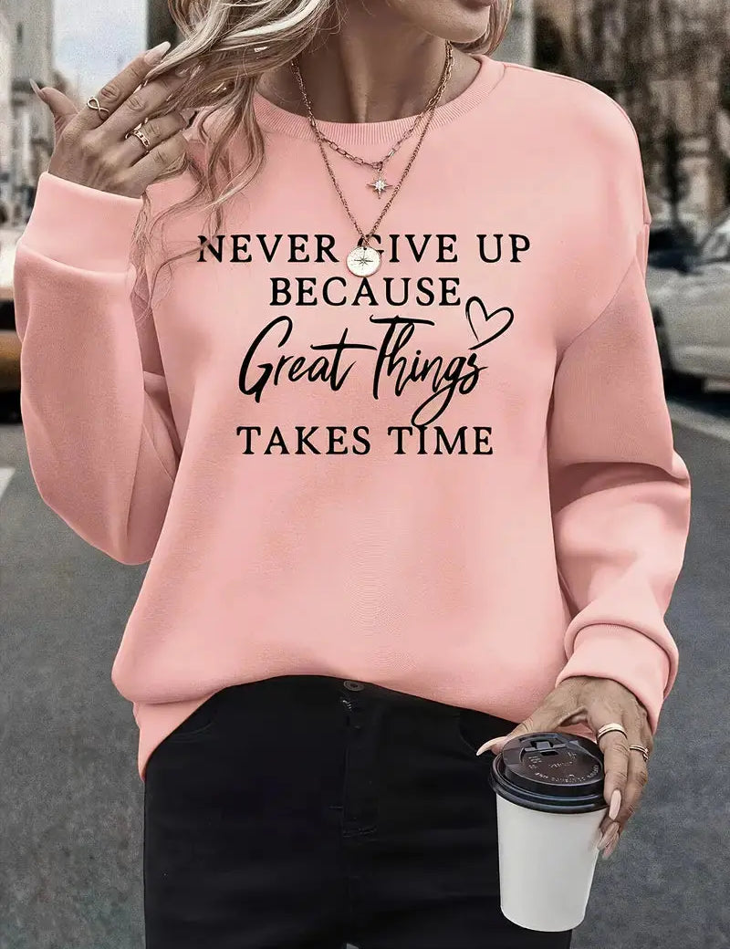 Donna con felpa rosa con scritta motivazionale, collane dorate, e caffè da asporto. Moda casual autunnale, abbigliamento streetwear femminile.