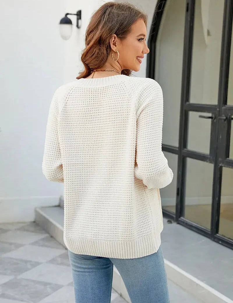 Donna con maglione bianco lavorato a maglia, maniche lunghe, davanti a porta nera. Moda autunnale, abbigliamento casual elegante.
