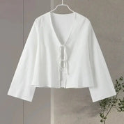Camicia bianca da donna con scollo a V e lacci, maniche lunghe ampie, design elegante e minimalista, perfetta per look casual e formali.