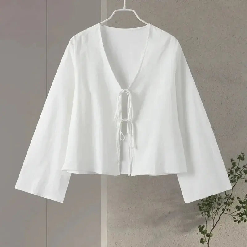 Camicia bianca da donna con scollo a V e lacci, maniche lunghe ampie, design elegante e minimalista, perfetta per look casual e formali.