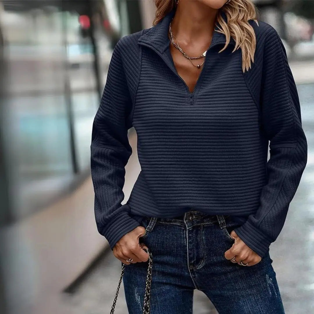 Donna con maglione a coste blu scuro, zip frontale, abbinato a jeans casual. Moda autunnale, abbigliamento femminile elegante e confortevole.