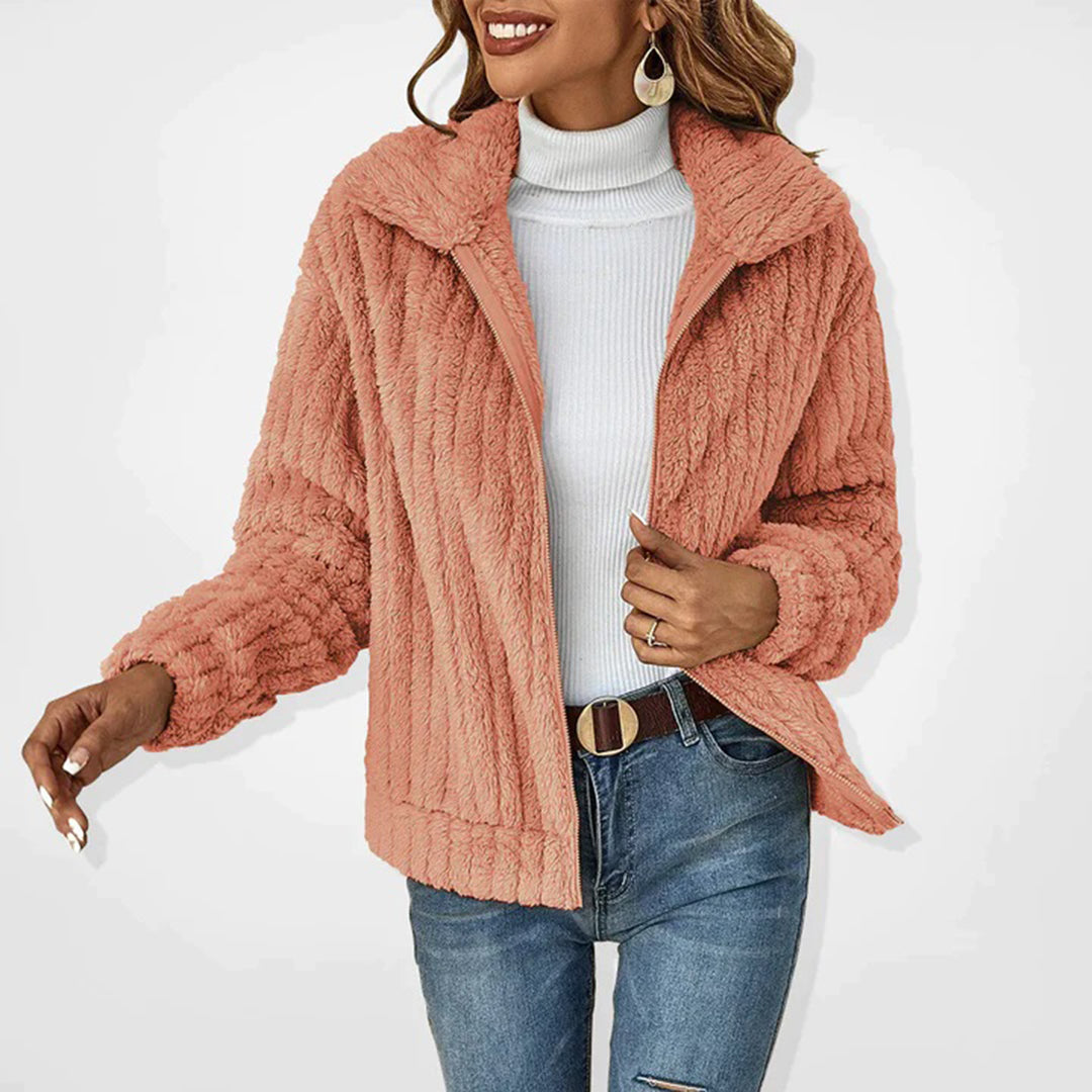 Giacca in pelliccia sintetica rosa donna, collo alto, abbinata a dolcevita bianco e jeans. Moda autunnale, stile casual elegante.
