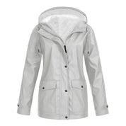 Giacca impermeabile donna grigia con cappuccio, chiusura a bottoni, tasche frontali. Ideale per pioggia, moda autunnale, abbigliamento outdoor.