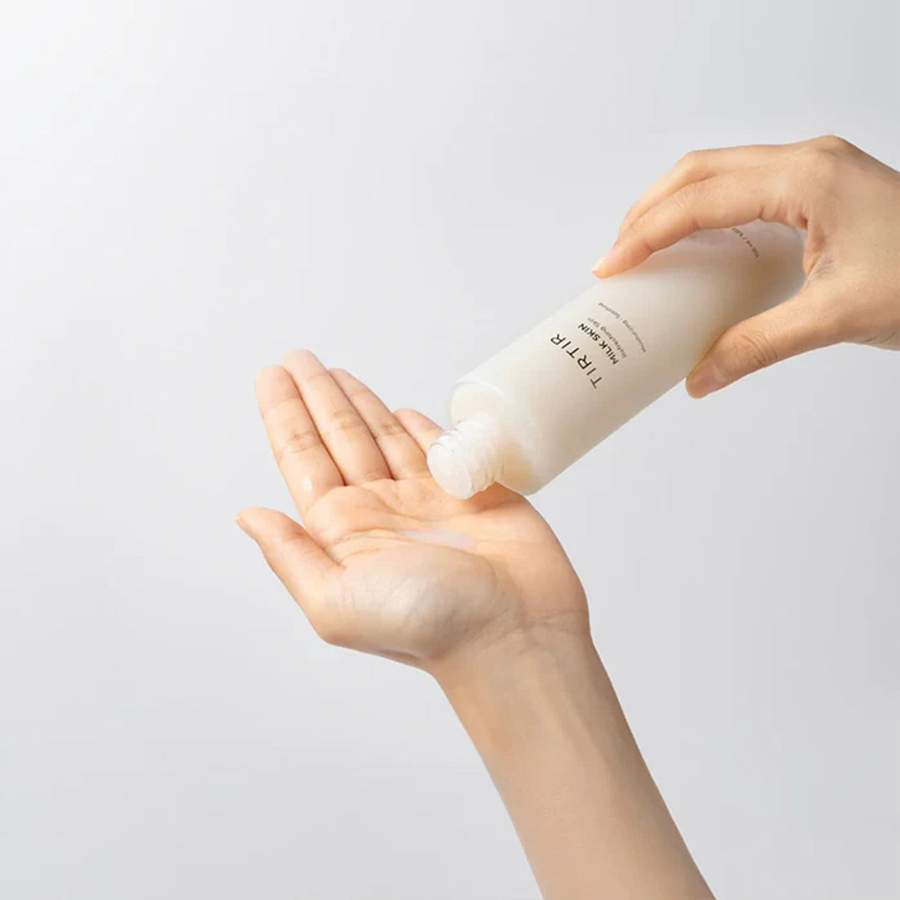 Mani versano tonico viso idratante incolore da flacone bianco su sfondo neutro. Cura della pelle, cosmetici, routine bellezza.