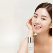 Donna sorridente con flacone di tonico TIRTIR Milk Skin, skincare idratante, pelle luminosa, bellezza coreana, cura del viso, cosmetici.