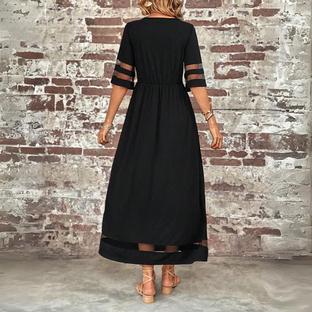 Abito lungo nero elegante con maniche trasparenti, indossato da donna di spalle, su sfondo di muro in mattoni. Moda femminile, abbigliamento chic.