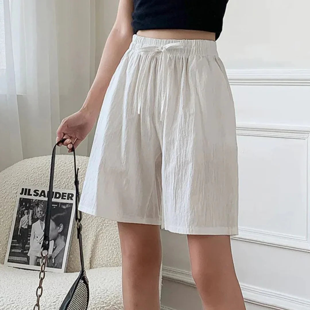 Pantaloncini bianchi da donna in cotone, vita alta con elastico, abbinati a top nero. Stile casual estivo, perfetti per look quotidiani.