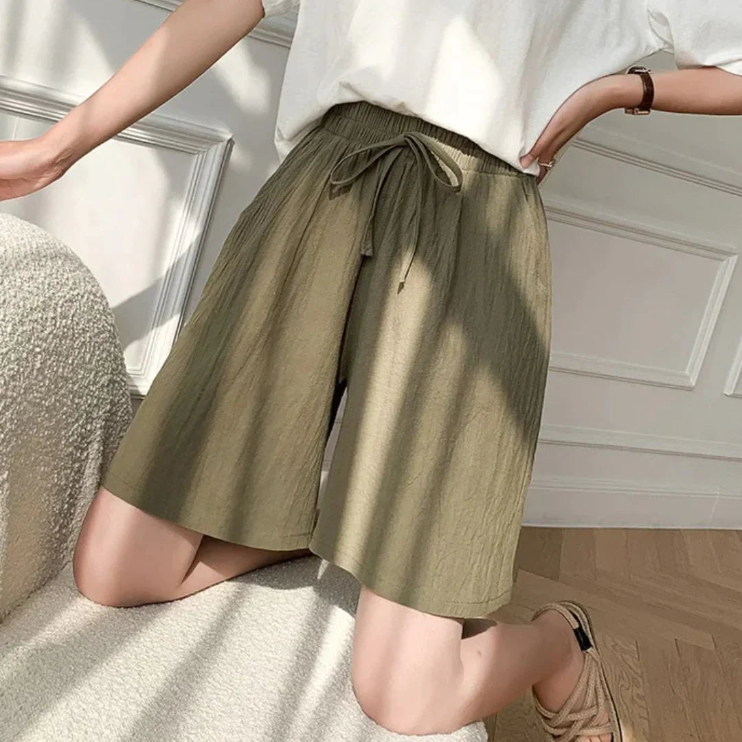 Pantaloncini donna verde oliva, vita alta con laccio, tessuto leggero, stile casual estivo, indossati con maglietta bianca.