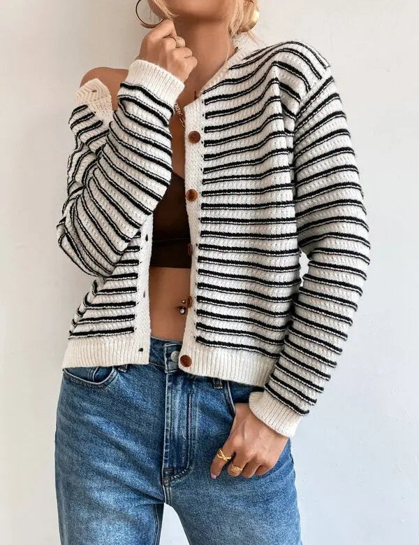 Donna con cardigan a righe bianche e nere, bottoni in legno, indossa jeans blu. Moda casual autunnale, stile moderno, abbigliamento femminile.