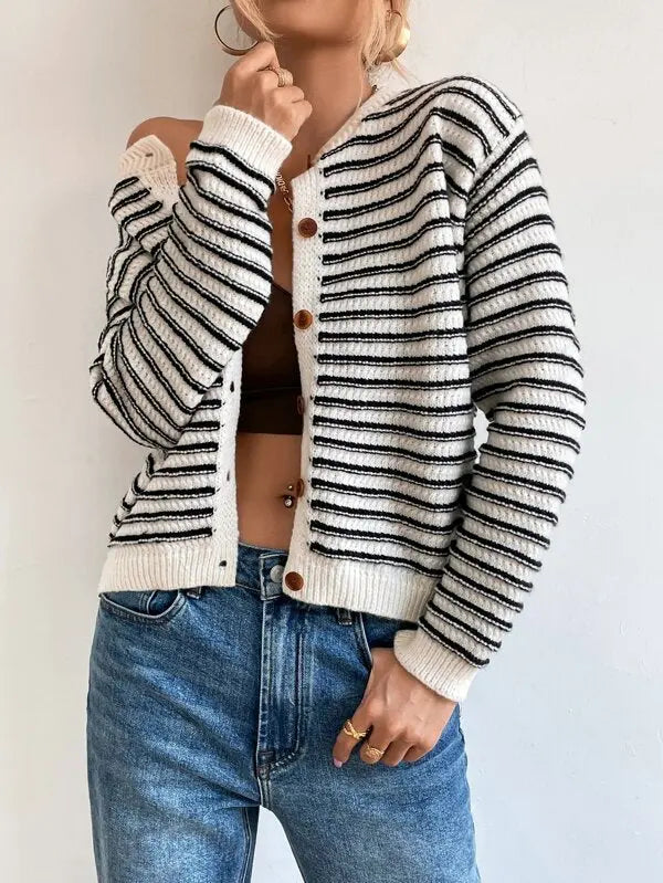 Donna con cardigan a righe bianche e nere, bottoni in legno, indossa jeans blu. Moda casual autunnale, stile moderno, abbigliamento femminile.