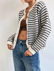 Donna con cardigan a righe bianche e nere, top marrone e jeans blu. Moda casual autunnale, abbigliamento femminile trendy, stile urbano.