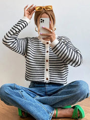 Donna con cardigan a righe bianche e nere, jeans blu e occhiali da sole gialli. Moda casual, stile autunnale, abbigliamento femminile trendy.